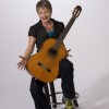 Photo of Sister Dorothy in casual wear, sitting on a stool with acoustic guitar